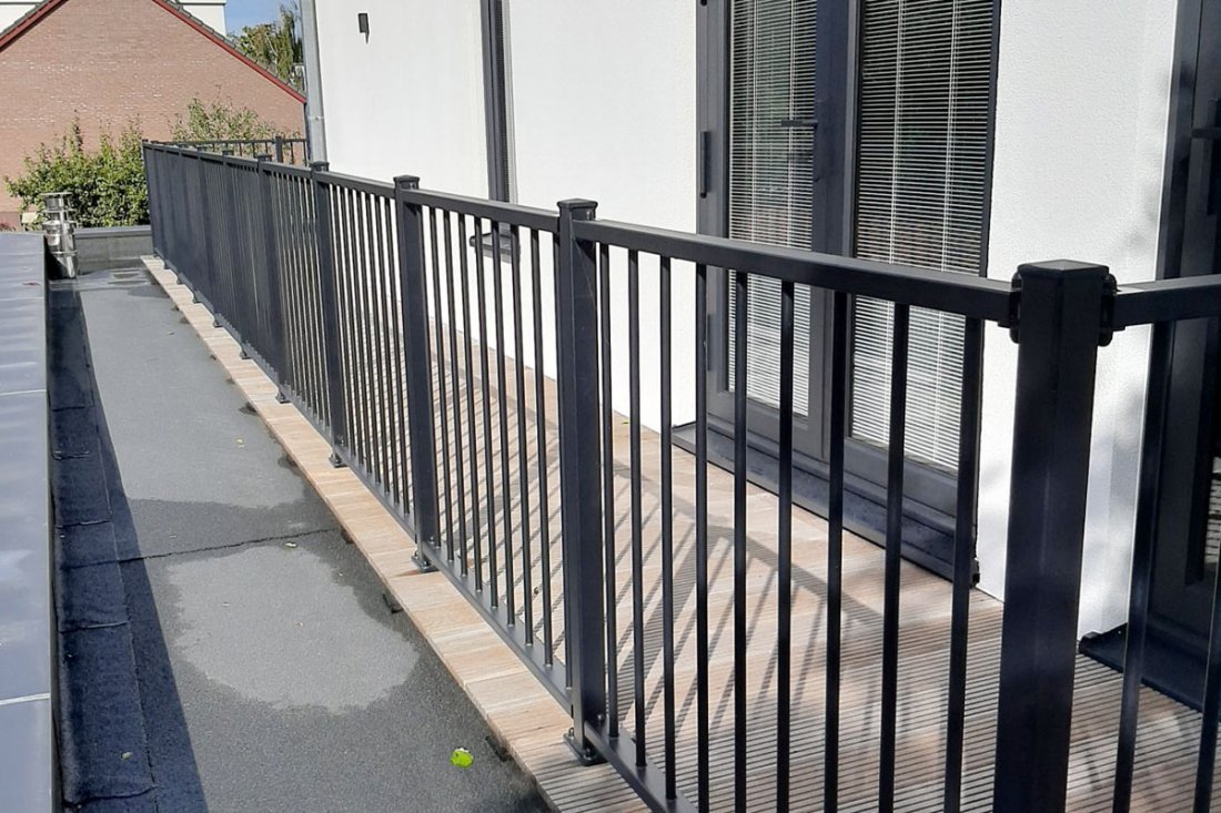 Wit balkonhekwerk langs een dakterras met een gecoate afwerking