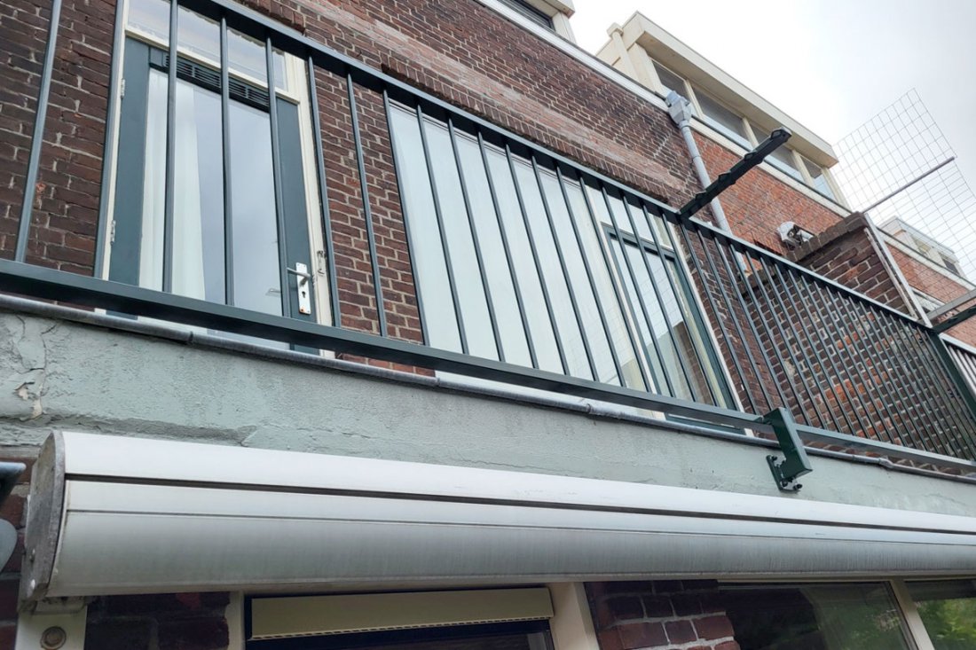 Balkonhekwerk met een brede bovenregel als leuning langs een dakterras