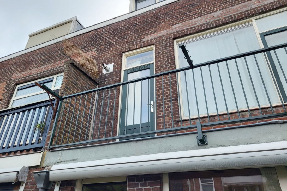 Balkonhekwerk in gedekte kleur bij een woning met bakstenen gevel