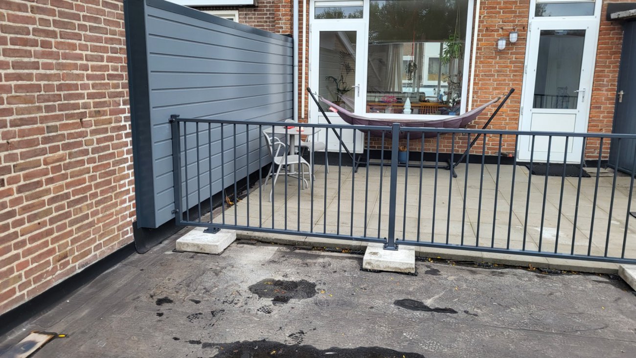 Zelf gemonteerd balkonhekwerk op een dakterras met voetplaten op de tegelvloer