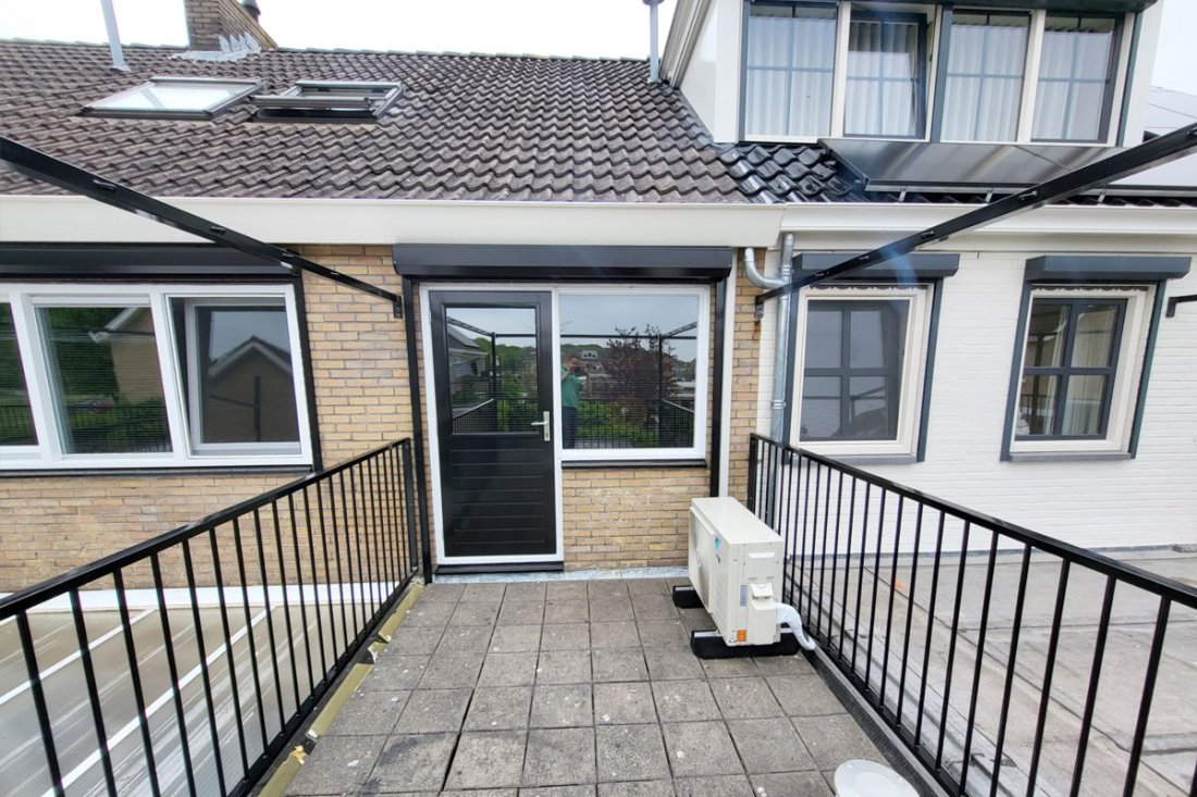 Zwart balkonhekwerk langs een terras achter een woning