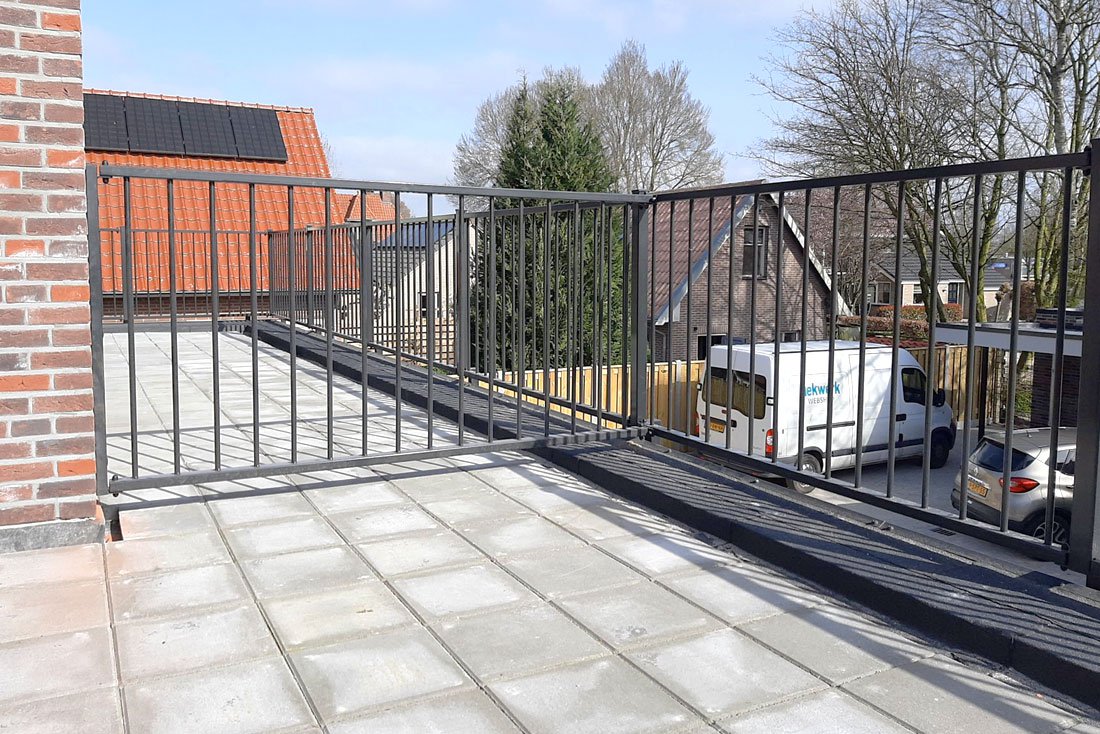 Hekwerk op een dakterras boven een aanbouw van een woning