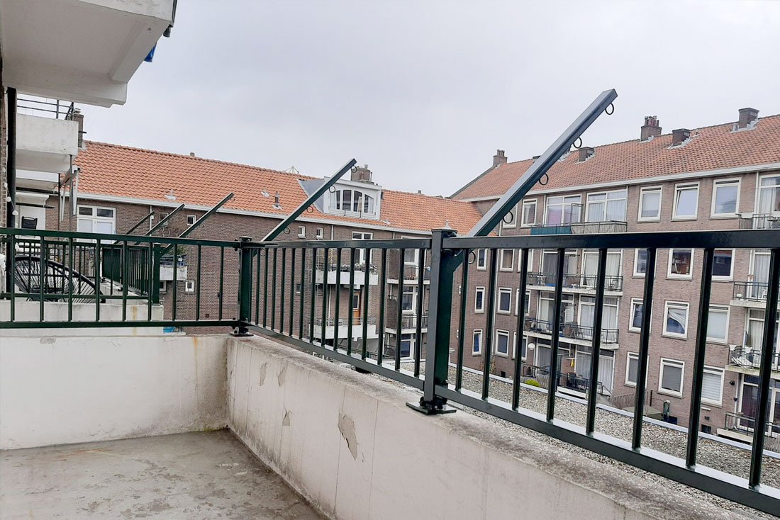 Hekwerk langs een dakterras boven een uitbouw in een woonwijk