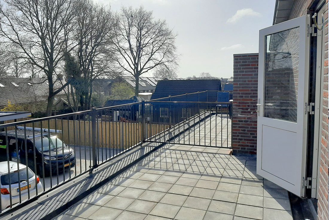 Dakterras met tegelvloer en hekwerk langs de rand