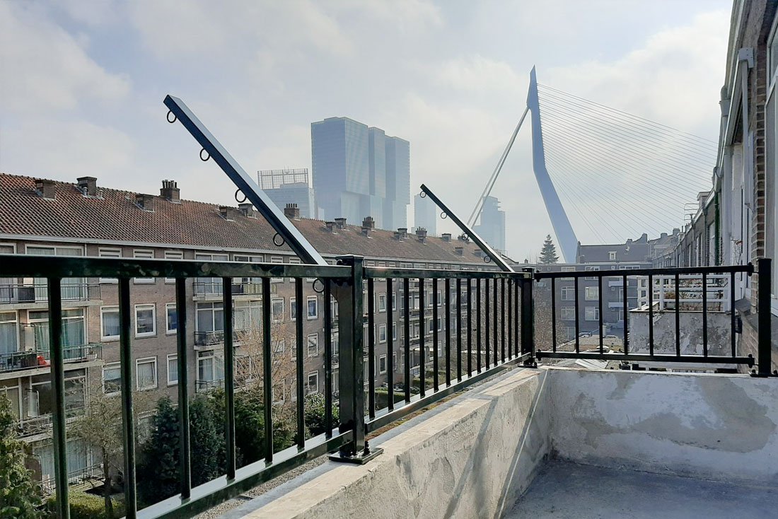 Hekwerk langs een dakterras met een opstand en tegels op dragers