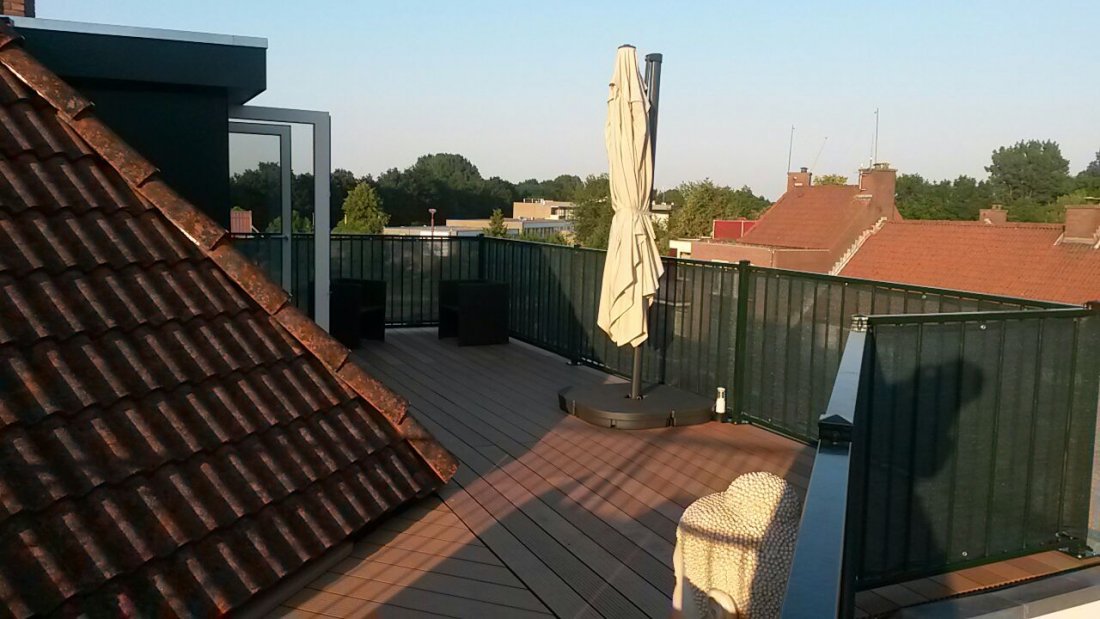 Hekwerk langs een dakterras met uitzicht over de daken