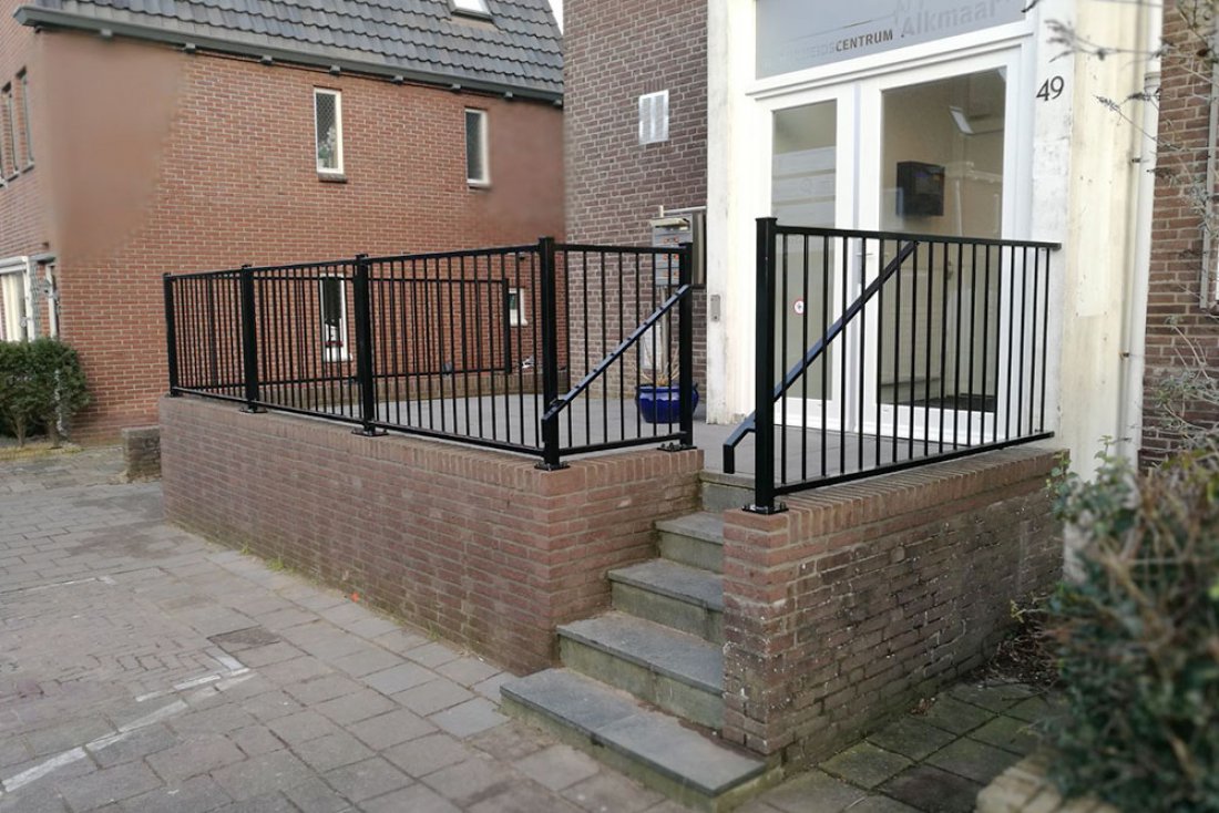 Hekwerk als afscheiding langs een gemetselde muur bij een gebouw