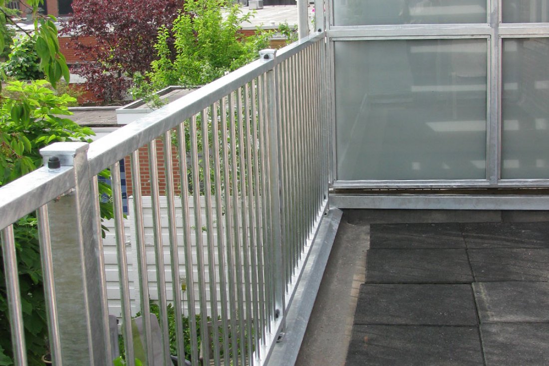 Hekwerk met glas en verticale spijlen langs een plat dak