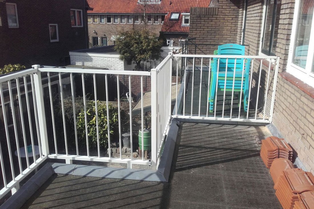 Wit spijlenhek rond een terras van een woning