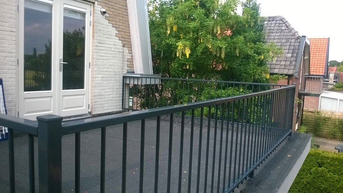 Hekwerk langs een balkon met beplanting bij een woning