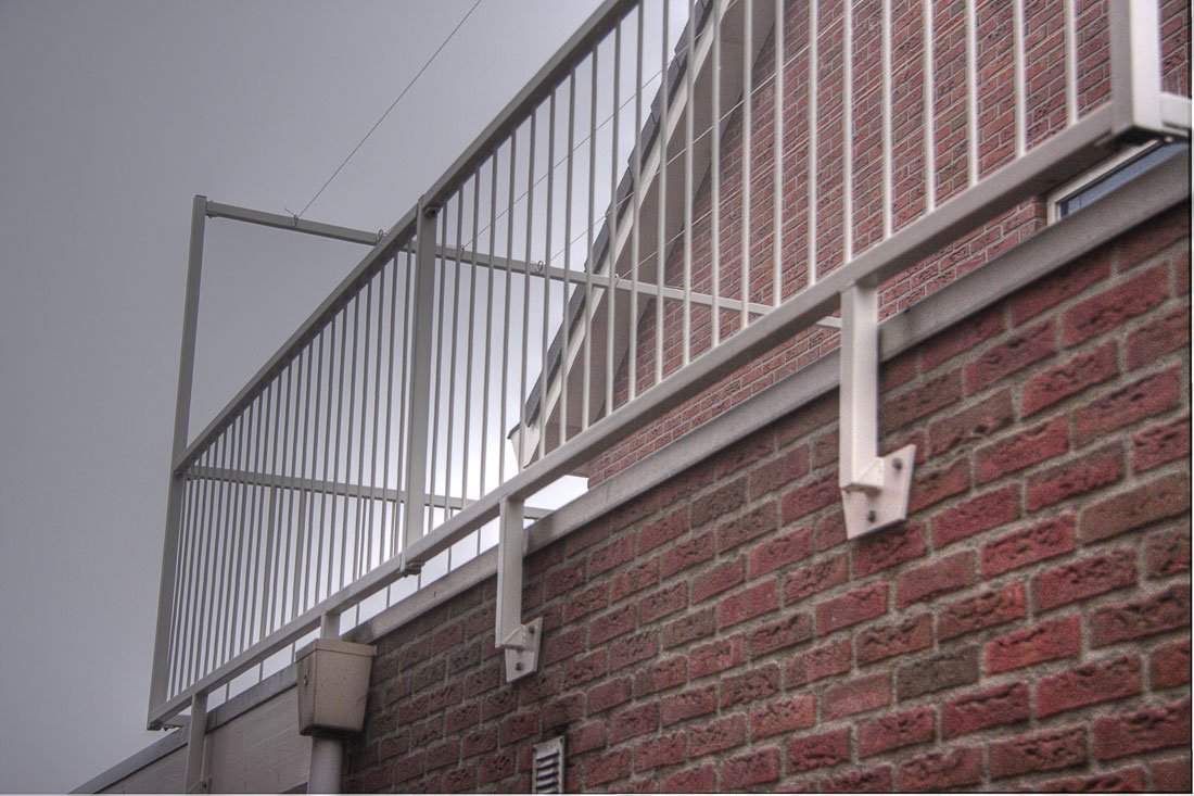 Hekwerk met een trap langs de gevel van een gebouw