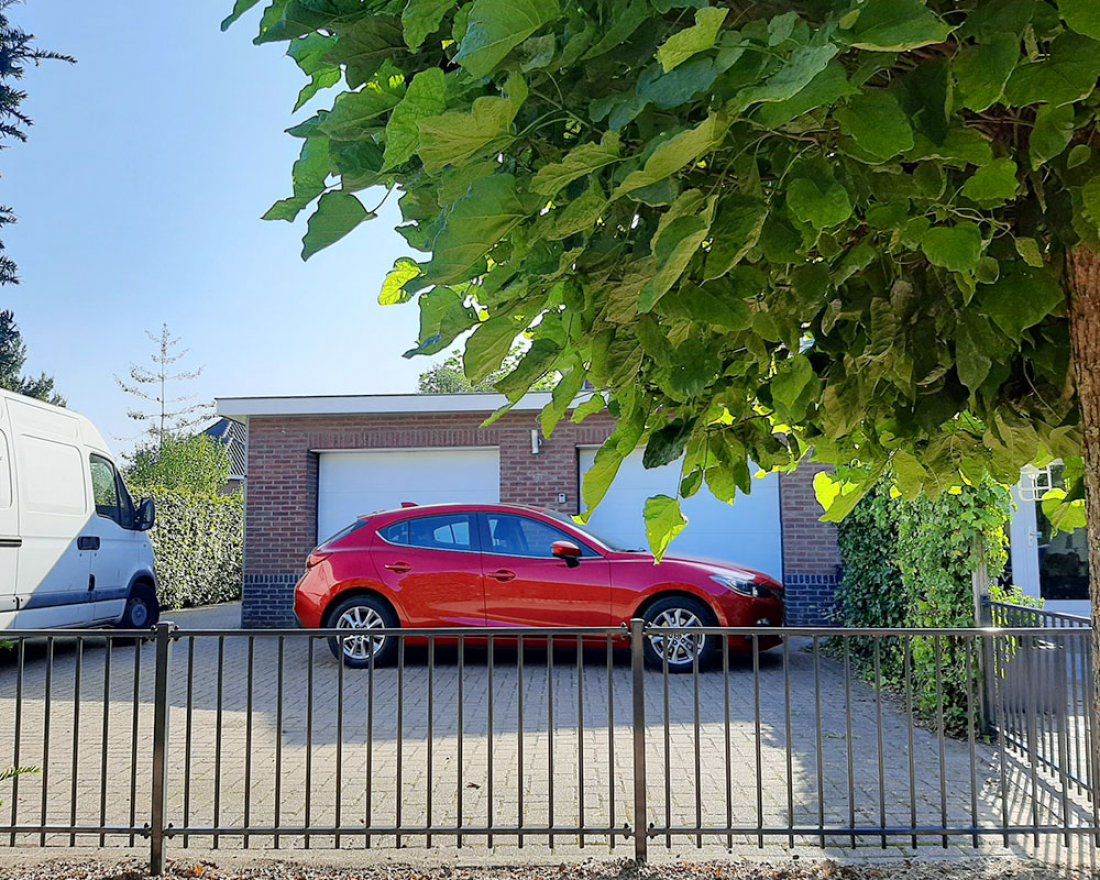 Tuinhekwerk met palen in de grond langs een tuinpad